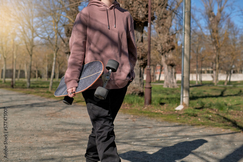 Girl walking through a park with a skateboard