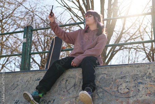 girl taking a selfie with her cell phone at a skate park
