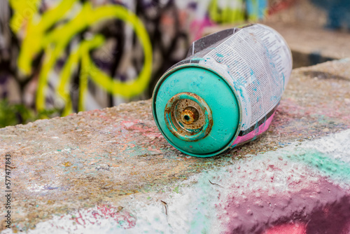 A discarded spray paint can sits in a graffiti covered urban area, urban decay, vandalism.