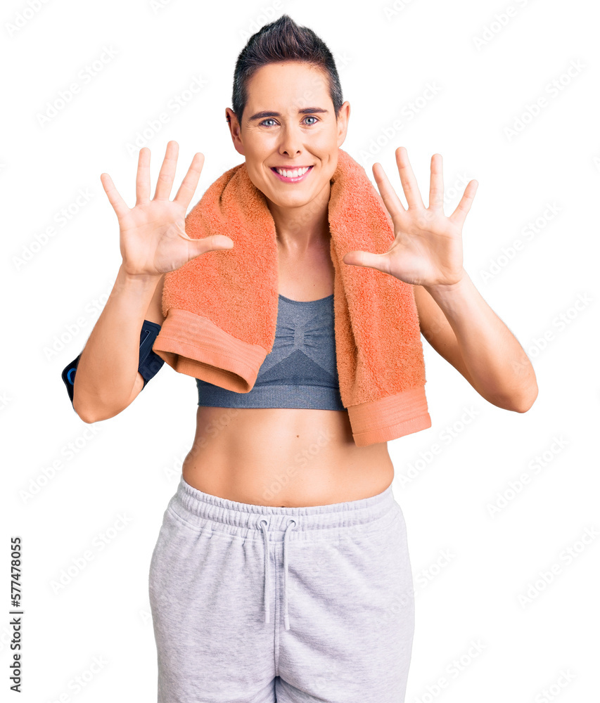 Young woman with short hair wearing sportswear and towel using smartphone showing and pointing up with fingers number ten while smiling confident and happy. Young woman with short hair wearing sportswear and towel using smartphone showing and pointing up with fingers number ten while smiling confident and happy.