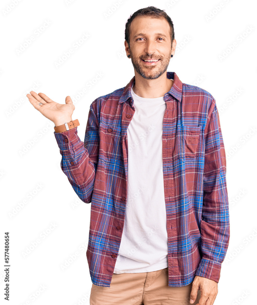 Young handsome man wearing casual clothes smiling cheerful presenting and pointing with palm of hand looking at the camera.