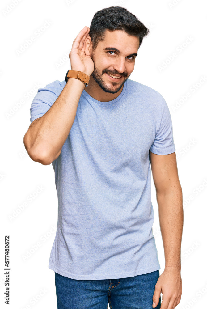 Young hispanic man wearing casual clothes smiling with hand over ear listening an hearing to rumor or gossip. deafness concept. Young hispanic man wearing casual clothes smiling with hand over ear listening an hearing to rumor or gossip. deafness concept.