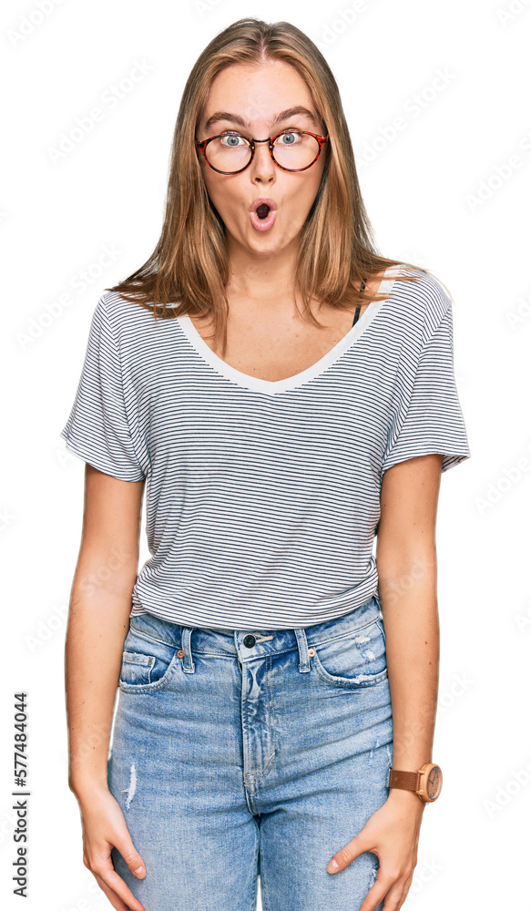 Beautiful young blonde woman wearing casual clothes and glasses afraid and shocked with surprise expression, fear and excited face. Beautiful young blonde woman wearing casual clothes and glasses afraid and shocked with surprise expression, fear and excited face.
