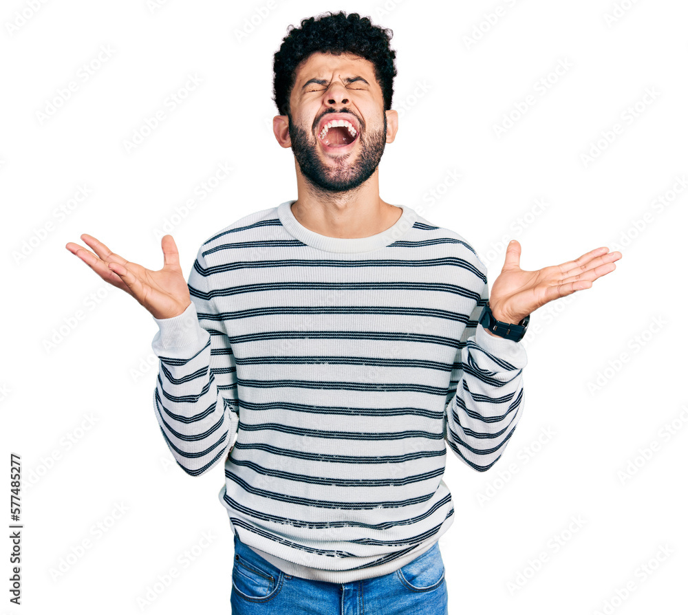 Young arab man with beard wearing casual striped sweater celebrating mad and crazy for success with arms raised and closed eyes screaming excited. winner concept Young arab man with beard wearing casual striped sweater celebrating mad and crazy for success with arms raised and closed eyes screaming excited. winner concept