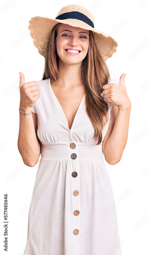 Young beautiful blonde woman wearing summer dress and hat success sign doing positive gesture with hand, thumbs up smiling and happy. cheerful expression and winner gesture. Young beautiful blonde woman wearing summer dress and hat success sign doing positive gesture with hand, thumbs up smiling and happy. cheerful expression and winner gesture.
