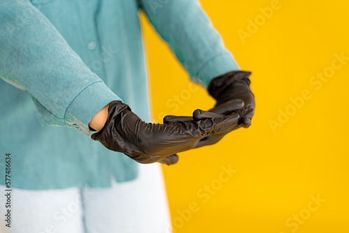Black nitrile protective glove, on a yellow background