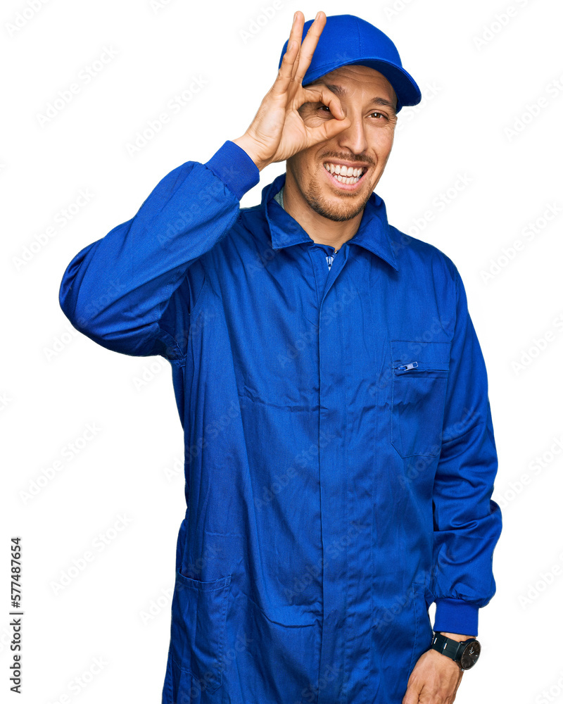 Bald man with beard wearing builder jumpsuit uniform doing ok gesture with hand smiling, eye looking through fingers with happy face. Bald man with beard wearing builder jumpsuit uniform doing ok gesture with hand smiling, eye looking through fingers with happy face.