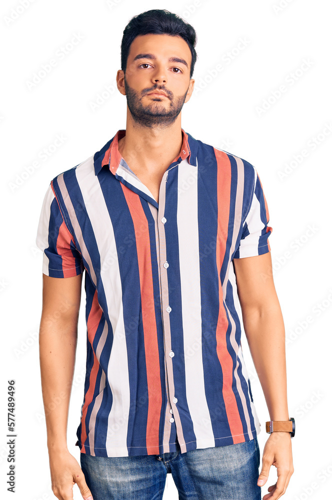 Fototapeta premium Young handsome hispanic man wearing casual summer shirt with serious expression on face. simple and natural looking at the camera.