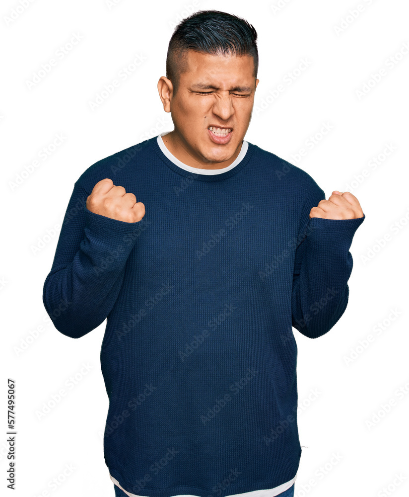 Young latin man wearing casual clothes excited for success with arms raised and eyes closed celebrating victory smiling. winner concept. Young latin man wearing casual clothes excited for success with arms raised and eyes closed celebrating victory smiling. winner concept.