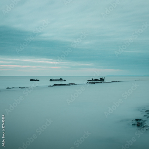 A coastal view of a rocky shore and a shipwreck