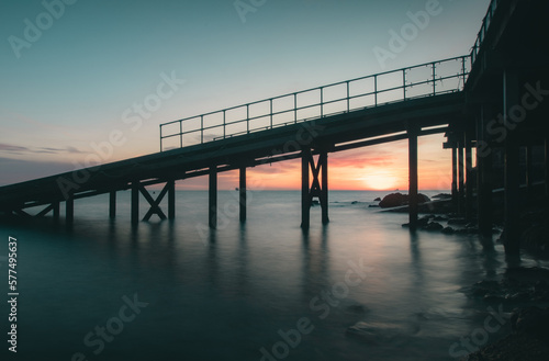 View of a pier leading out at sea at sunrise. © harry