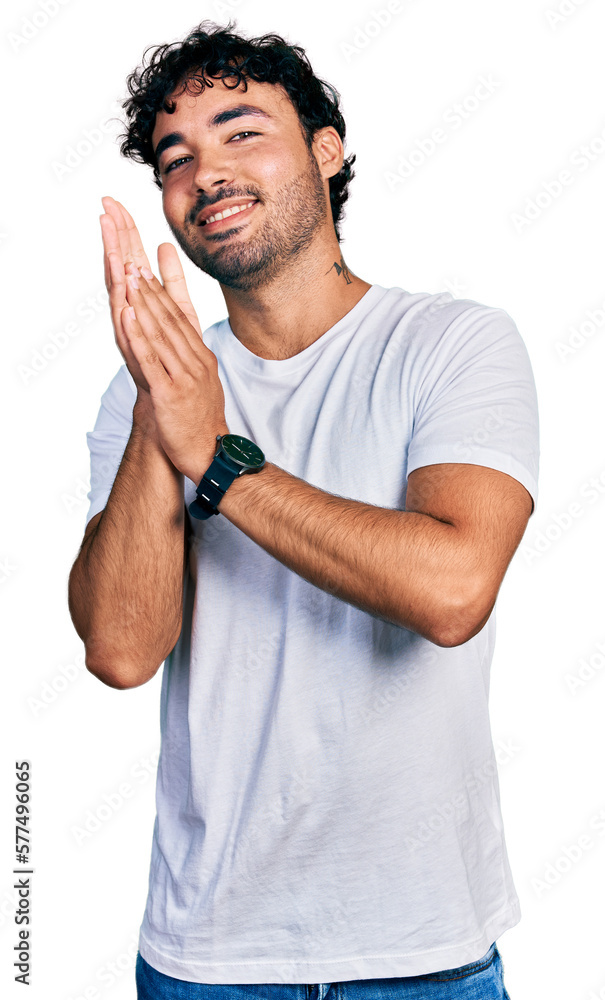 Hispanic young man with beard wearing casual white t shirt clapping and applauding happy and joyful, smiling proud hands together Hispanic young man with beard wearing casual white t shirt clapping and applauding happy and joyful, smiling proud hands together