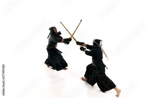 Top view. Dynamic image of two men, professional kendo athletes in uniform training with shinai sword against white studio background. Concept of martial arts, sport, Japanese culture, action, motion