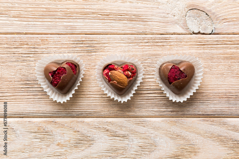 chocolate sweets in the form of a heart with fruits and nuts on a colored background. top view with space for text, holiday concept chocolate sweets in the form of a heart with fruits and nuts on a colored background. top view with space for text, holiday concept