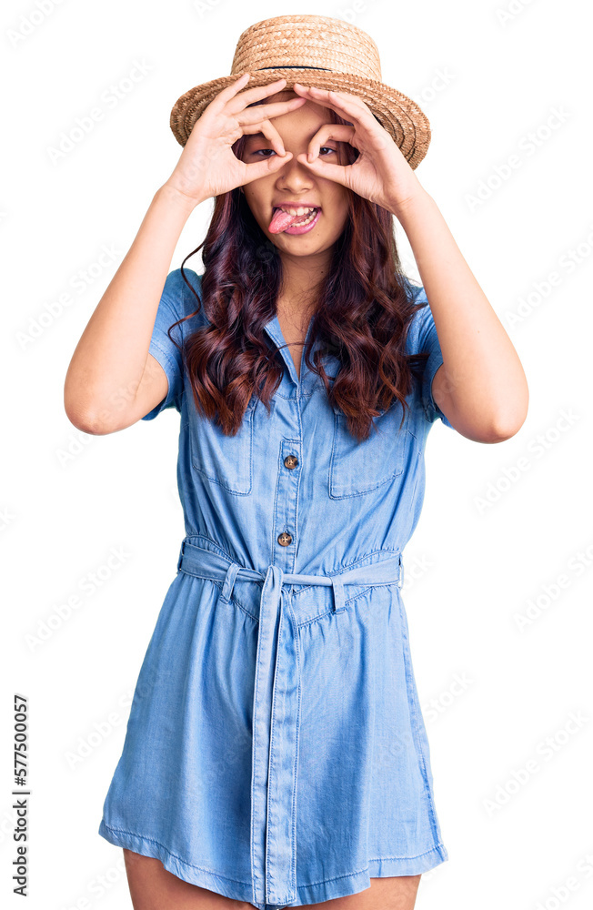 Young beautiful chinese girl wearing summer hat doing ok gesture like binoculars sticking tongue out, eyes looking through fingers. crazy expression. Young beautiful chinese girl wearing summer hat doing ok gesture like binoculars sticking tongue out, eyes looking through fingers. crazy expression.