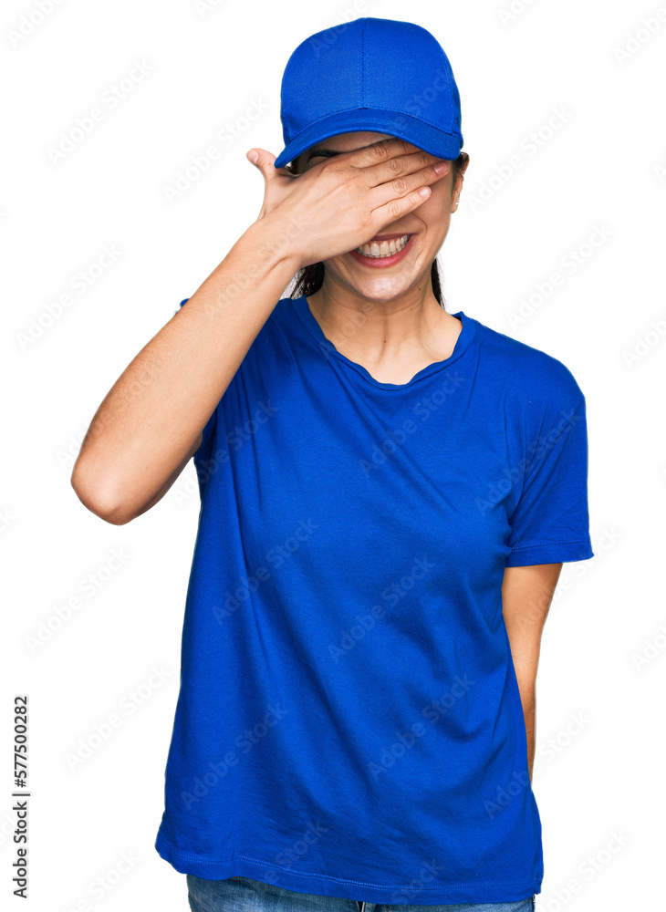 Young hispanic girl wearing delivery courier uniform smiling and laughing with hand on face covering eyes for surprise. blind concept. Young hispanic girl wearing delivery courier uniform smiling and laughing with hand on face covering eyes for surprise. blind concept.