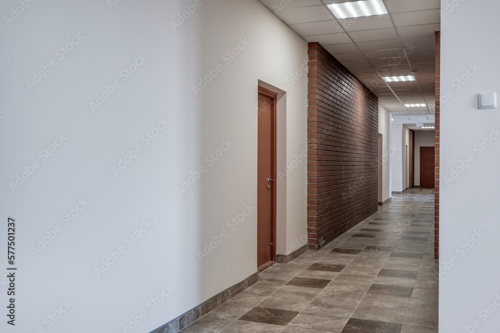 Fototapeta premium empty long corridor with red brick walls in interior of modern apartments, office or clinic.