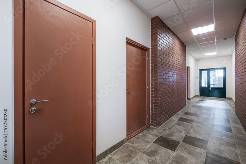 empty long corridor with red brick walls in interior of modern apartments  office or clinic.