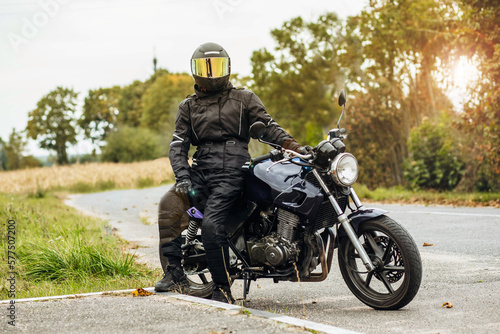 Obraz na płótnie motorcyclist in motorcycle clothing and a helmet on an old motorcycle cafe racer in the summer on the road w salonie