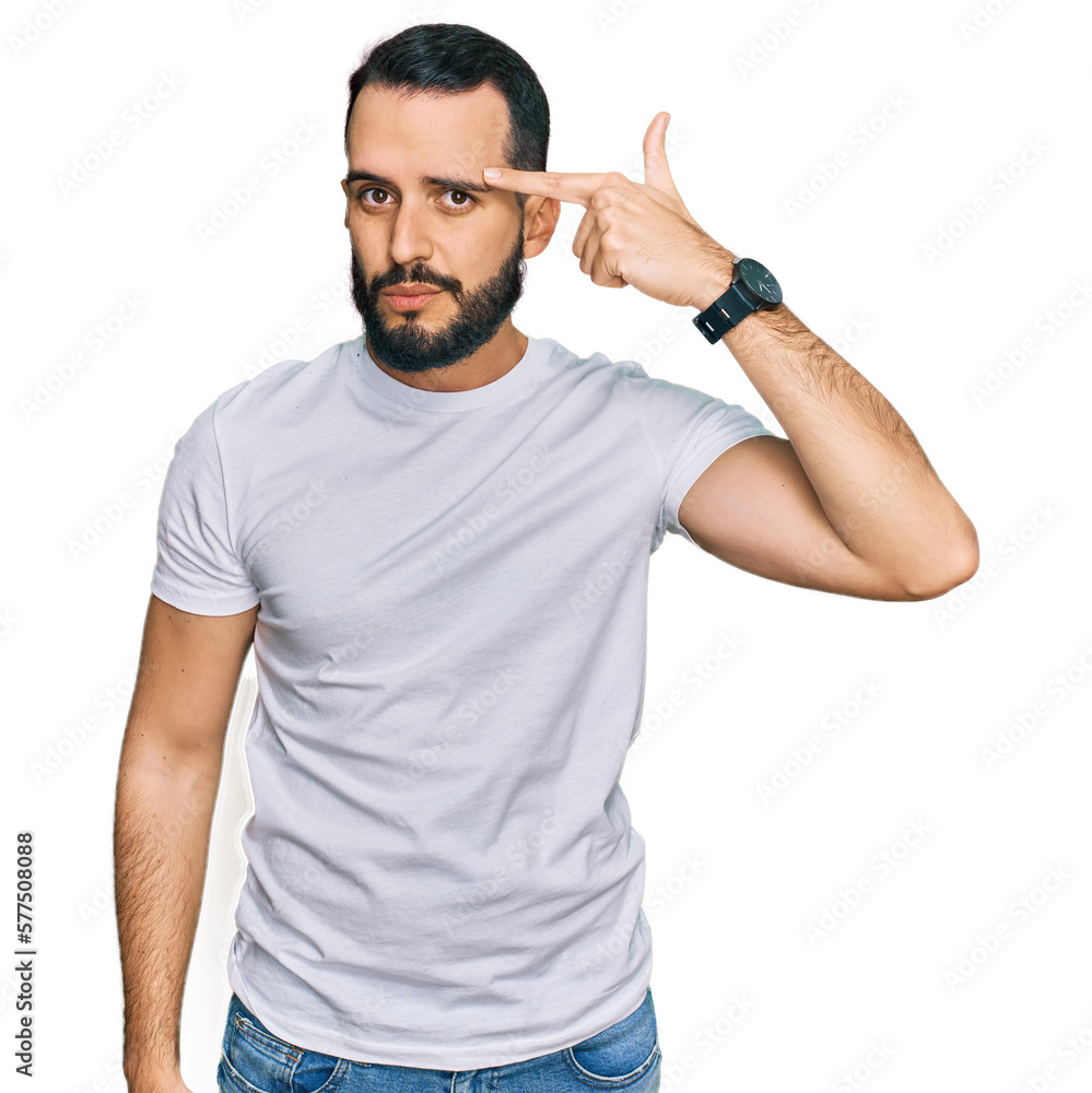 Young man with beard wearing casual white t shirt pointing unhappy to pimple on forehead, ugly infection of blackhead. acne and skin problem Young man with beard wearing casual white t shirt pointing unhappy to pimple on forehead, ugly infection of blackhead. acne and skin problem
