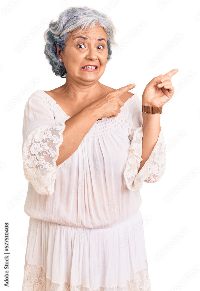 Senior woman with gray hair wearing bohemian style pointing aside worried and nervous with both hands, concerned and surprised expression Senior woman with gray hair wearing bohemian style pointing aside worried and nervous with both hands, concerned and surprised expression