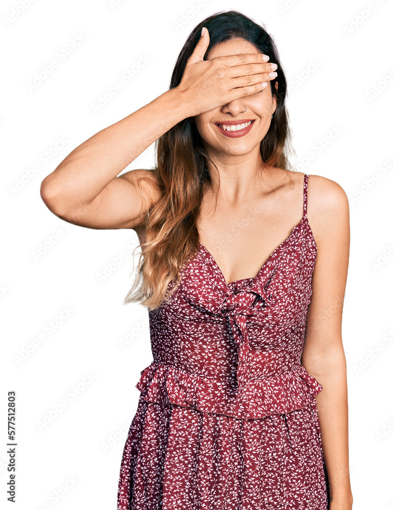 Beautiful hispanic woman wearing summer dress smiling and laughing with hand on face covering eyes for surprise. blind concept. Beautiful hispanic woman wearing summer dress smiling and laughing with hand on face covering eyes for surprise. blind concept.