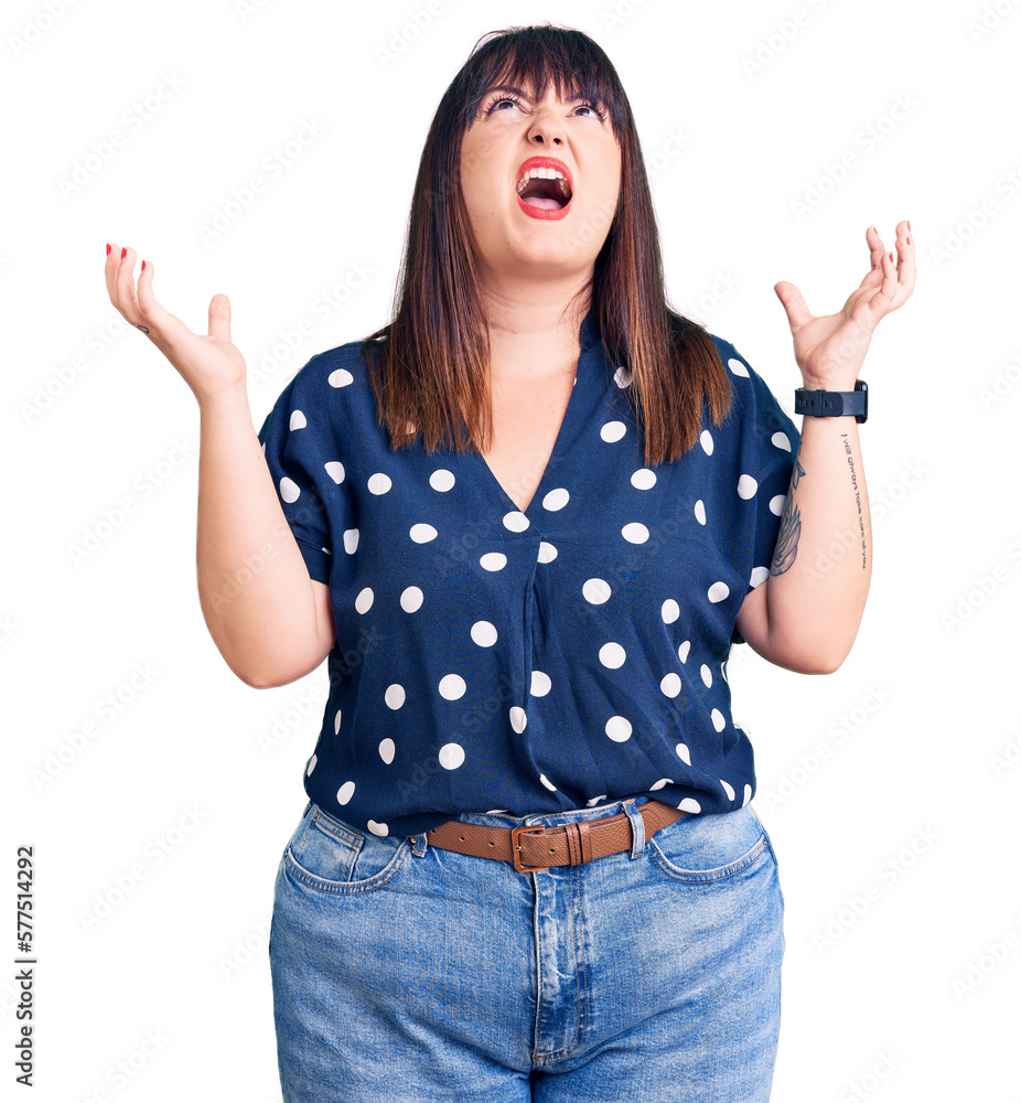 Young plus size woman wearing casual clothes crazy and mad shouting and yelling with aggressive expression and arms raised. frustration concept. Young plus size woman wearing casual clothes crazy and mad shouting and yelling with aggressive expression and arms raised. frustration concept.
