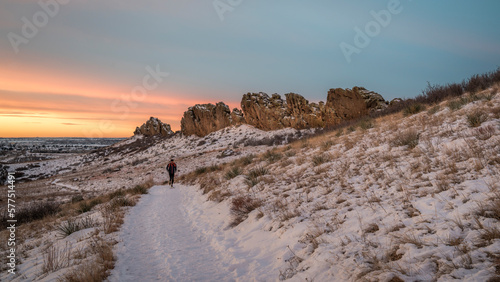 winter sunrise over a trail at Colorado foothills with a distant runner - Devils Backbone rock formation near Loveland