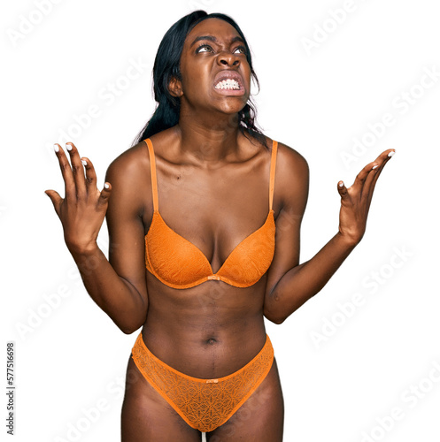 Young african american woman wearing lingerie crazy and mad shouting and yelling with aggressive expression and arms raised. frustration concept.