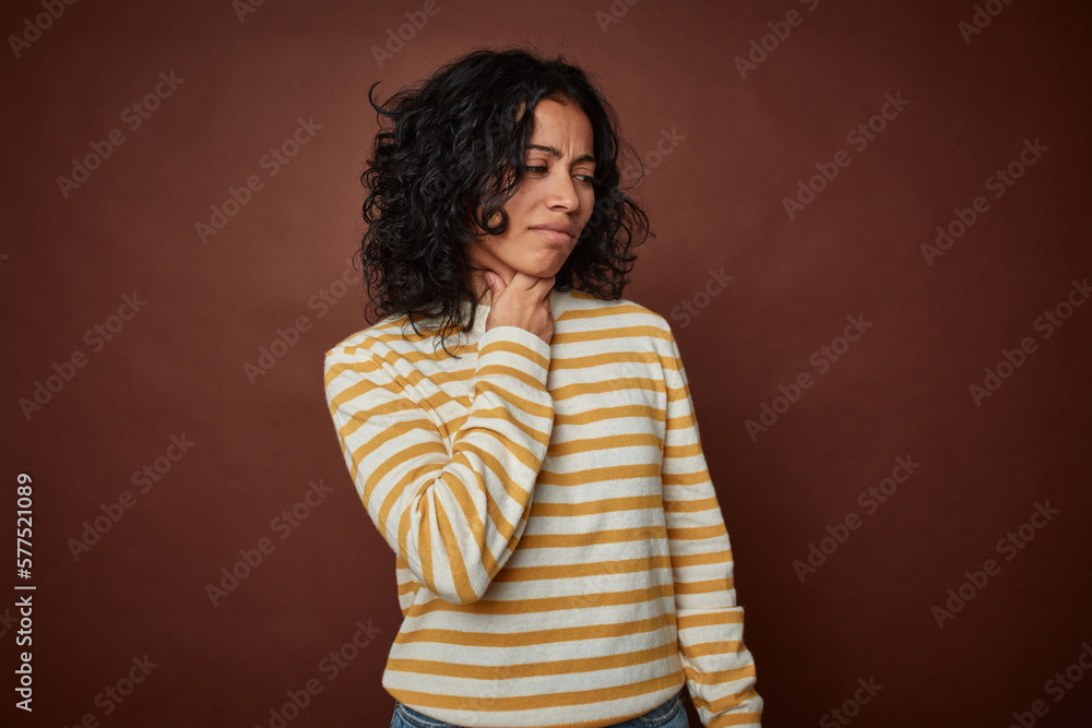 Young colombian curly hair woman isolated on brown background suffers pain in throat due a virus or infection.