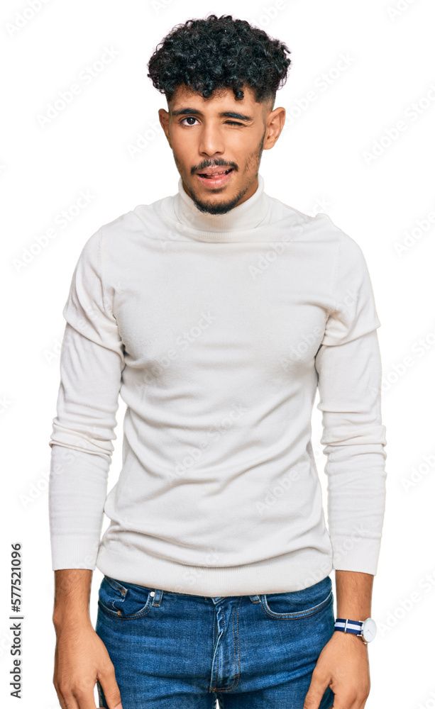 Young arab man wearing casual winter sweater winking looking at the camera with sexy expression, cheerful and happy face. Young arab man wearing casual winter sweater winking looking at the camera with sexy expression, cheerful and happy face.