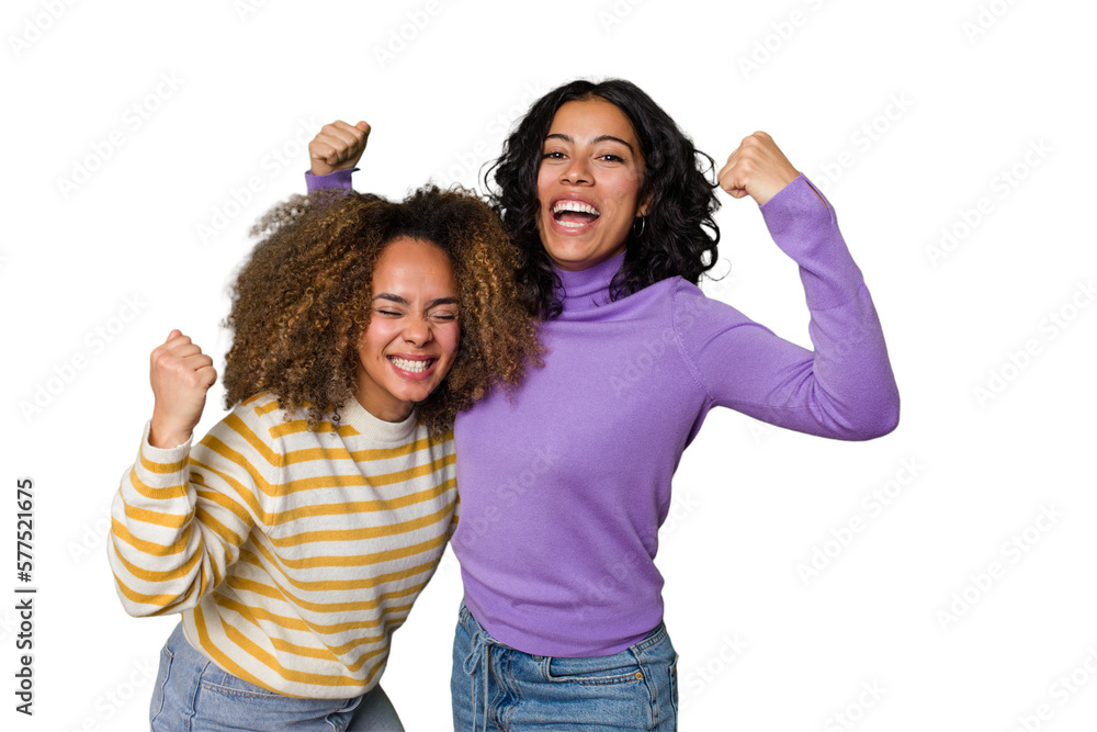 Two female friends isolated in studio raising fist after a victory, winner concept. Two female friends isolated in studio raising fist after a victory, winner concept.