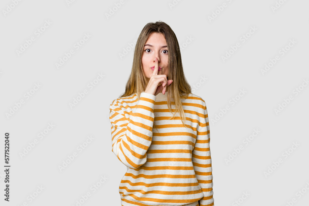 Young blonde posing for a portrait isolated, exuding natural beauty and radiance keeping a secret or asking for silence. Young blonde posing for a portrait isolated, exuding natural beauty and radiance keeping a secret or asking for silence.