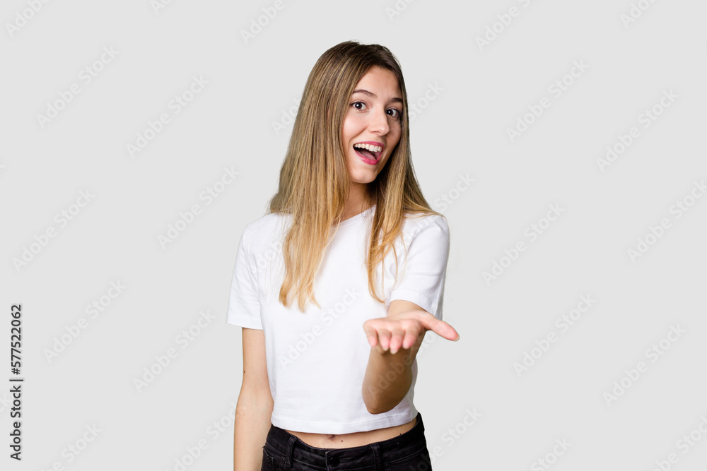 Young blonde posing for a portrait isolated, exuding natural beauty and radiance stretching hand at camera in greeting gesture. Young blonde posing for a portrait isolated, exuding natural beauty and radiance stretching hand at camera in greeting gesture.
