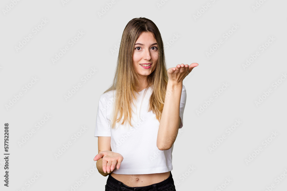 Young blonde posing for a portrait isolated, exuding natural beauty and radiance makes scale with arms, feels happy and confident. Young blonde posing for a portrait isolated, exuding natural beauty and radiance makes scale with arms, feels happy and confident.