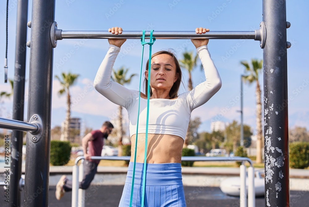 Active lifestyle. Slim young woman training pull ups with resistance band in outdoors gym at sunny summer day. Be H3althy. High quality photo Active lifestyle. Slim young woman training pull ups with resistance band in outdoors gym at sunny summer day. Be H3althy. High quality photo