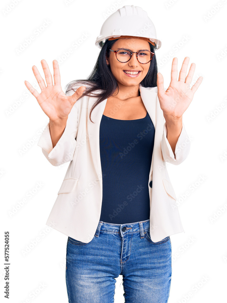 Young beautiful latin girl wearing architect hardhat and glasses afraid and terrified with fear expression stop gesture with hands, shouting in shock. panic concept. Young beautiful latin girl wearing architect hardhat and glasses afraid and terrified with fear expression stop gesture with hands, shouting in shock. panic concept.