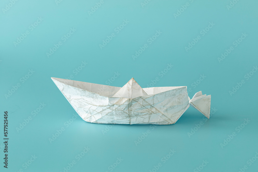 Isolate white paper boat almost destroyed on blue background. concept: keep going, be brave, courage, motivation, feel especial. 