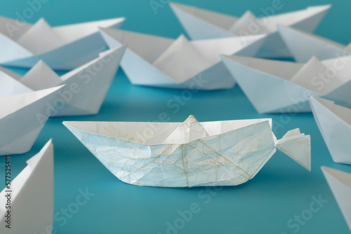 White paper boat almost destroyed on whites paper boats on blue background. concept  keep going  be brave  courage  motivation  feel especial. 