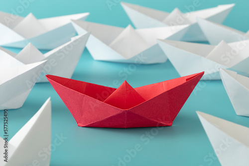 Red color paper ship on blue background on white paper boats. Concept: Make the difference, be yourself, against to the rule, think different, be brave, one in a million.
