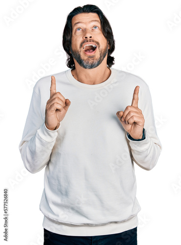 Middle age caucasian man wearing casual clothes amazed and surprised looking up and pointing with fingers and raised arms.
