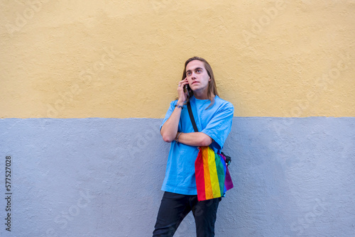 Man talking on the phone while wearing a belt bag with the lgbt rainbow flag.