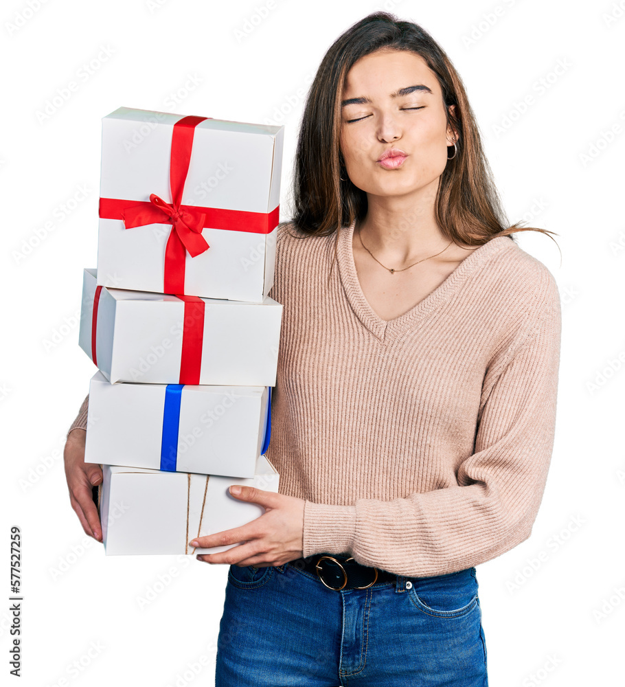 Young caucasian girl holding gifts looking at the camera blowing a kiss being lovely and sexy. love expression.