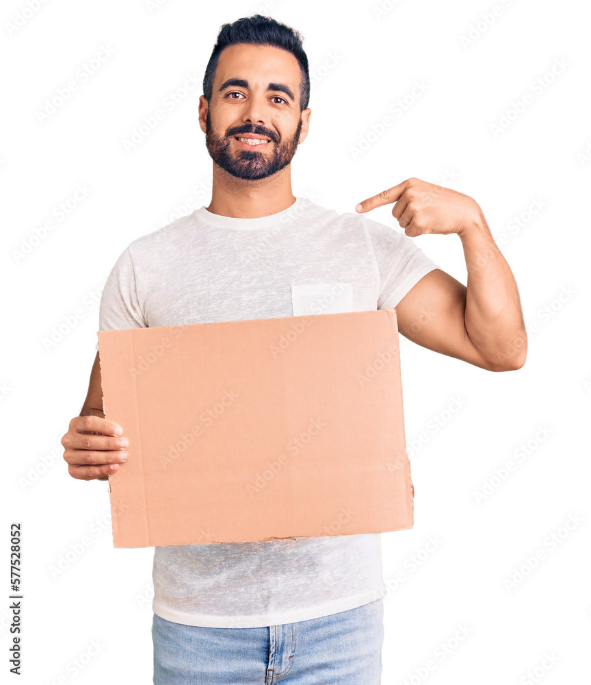 Young hispanic man holding banner cardboard pointing finger to one self smiling happy and proud Young hispanic man holding banner cardboard pointing finger to one self smiling happy and proud