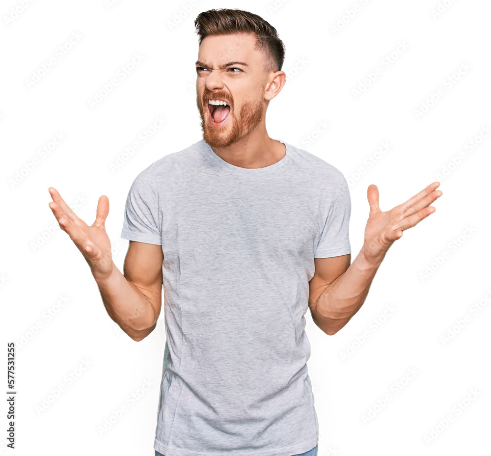 Young redhead man wearing casual grey t shirt crazy and mad shouting and yelling with aggressive expression and arms raised. frustration concept. Young redhead man wearing casual grey t shirt crazy and mad shouting and yelling with aggressive expression and arms raised. frustration concept.