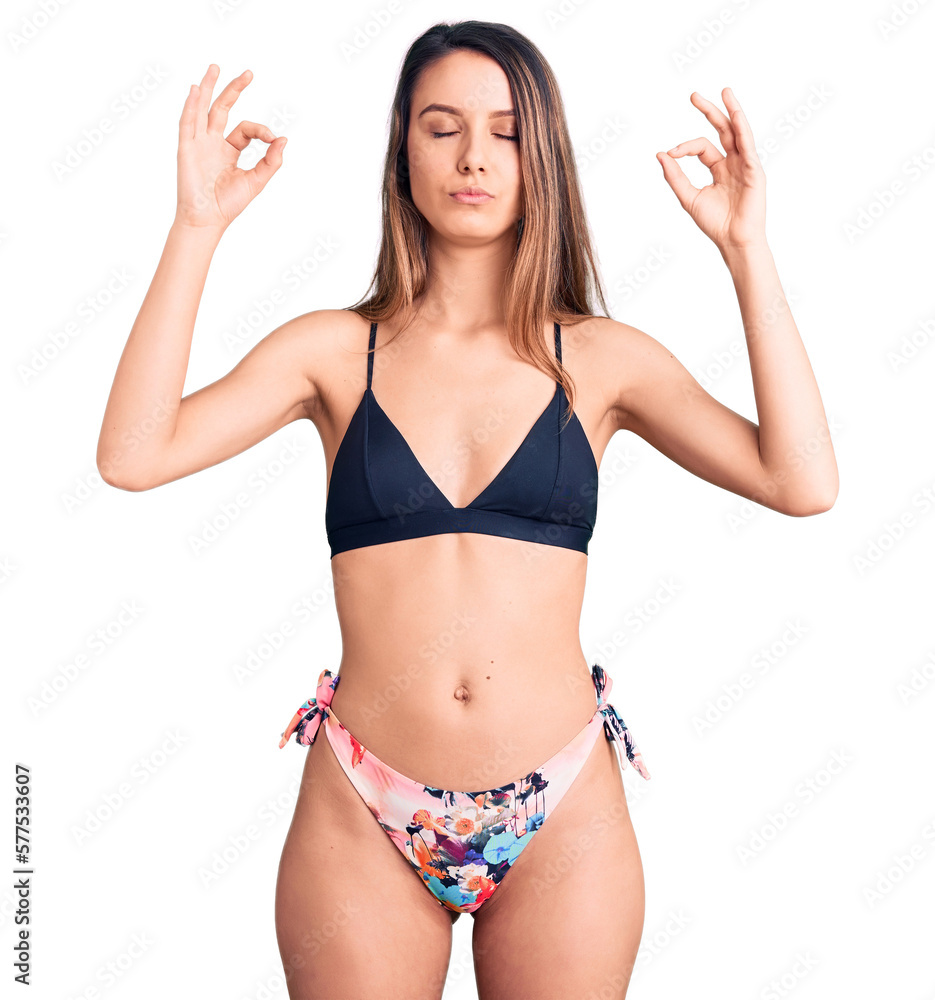 Young beautiful girl wearing bikini relax and smiling with eyes closed doing meditation gesture with fingers. yoga concept. Young beautiful girl wearing bikini relax and smiling with eyes closed doing meditation gesture with fingers. yoga concept.