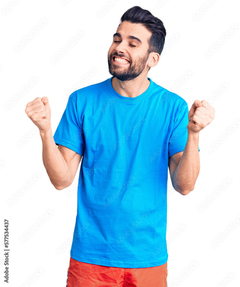 Young handsome man with beard wearing casual t-shirt very happy and excited doing winner gesture with arms raised, smiling and screaming for success. celebration concept. Young handsome man with beard wearing casual t-shirt very happy and excited doing winner gesture with arms raised, smiling and screaming for success. celebration concept.
