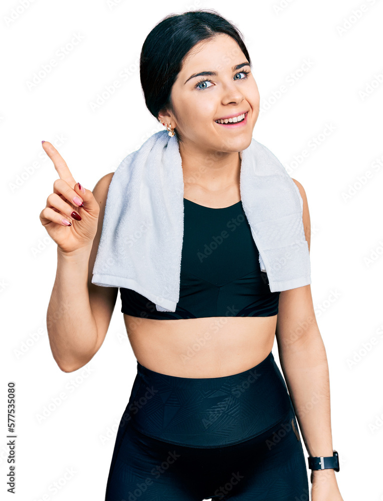 Young brunette woman with blue eyes wearing sportswear and towel showing and pointing up with finger number one while smiling confident and happy. Young brunette woman with blue eyes wearing sportswear and towel showing and pointing up with finger number one while smiling confident and happy.