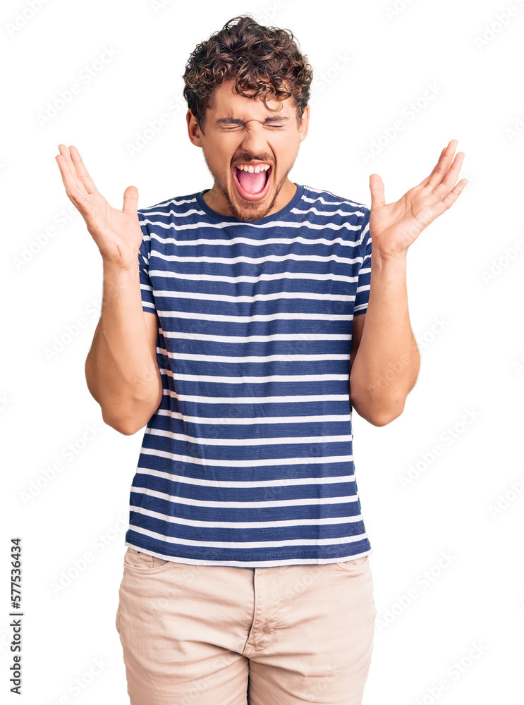 Young handsome man with curly hair wearing casual clothes celebrating mad and crazy for success with arms raised and closed eyes screaming excited. winner concept Young handsome man with curly hair wearing casual clothes celebrating mad and crazy for success with arms raised and closed eyes screaming excited. winner concept