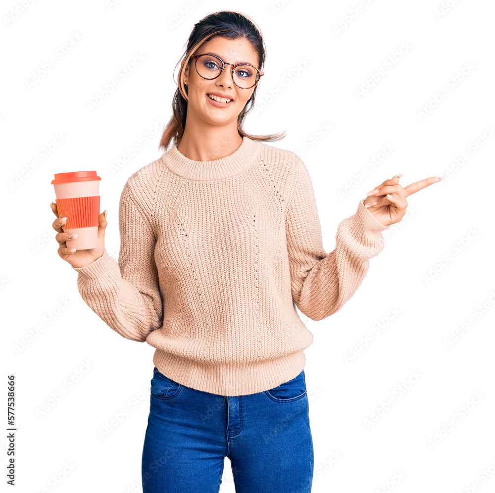 Young beautiful woman wearing glasses holding takeaway cup of coffee smiling happy pointing with hand and finger to the side Young beautiful woman wearing glasses holding takeaway cup of coffee smiling happy pointing with hand and finger to the side